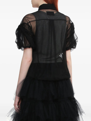 A person wearing a sheer black cropped shirt with puffy sleeves from Simone Rocha