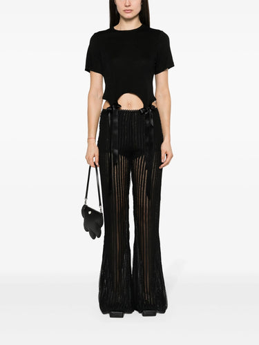 Person wearing a black cut-out top from Simone Rocha and black flared pants on a white background