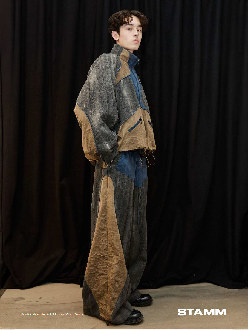 Model wearing the Stamm Exchange Center Vibe Jacket in Grey/Blue/Brown with matching trousers, showing the oversized technical silhouette and panelled construction.
