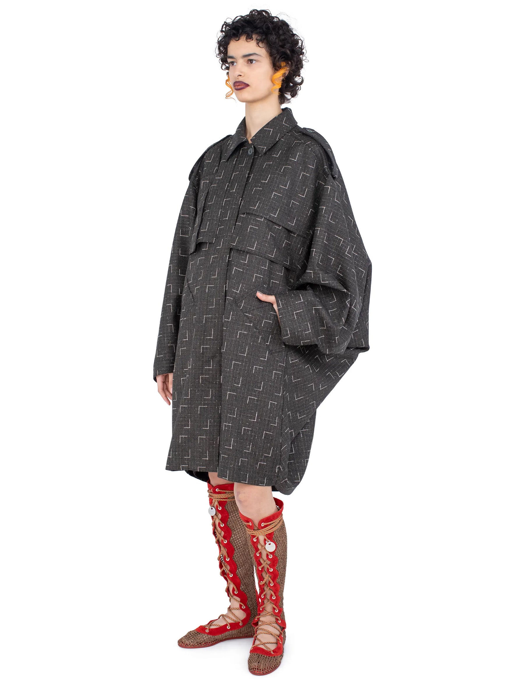 Side view of the model wearing the Kiko Kostadinov Statsinger Coat in Off Black & Chalk.