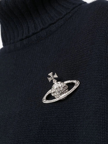 Closeup of model wearing Vivienne Westwood Bas Relief Brooch in platinum, showcasing silver-tone orb motif and pavé crystal detailing.