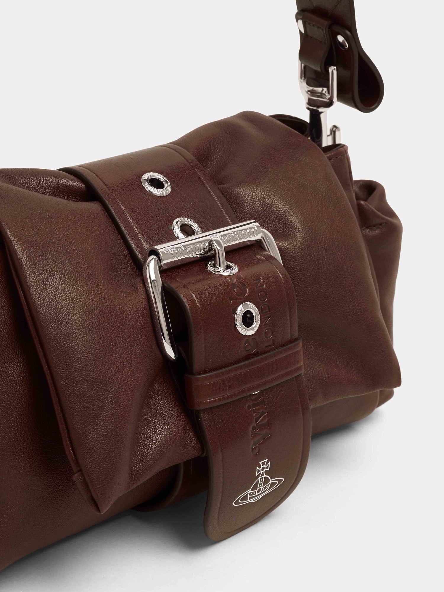 Close-up of Vivienne Westwood Hazel Treasure Handbag in chestnut leather showing sculptural belt fastening, metal buckle and embossed orb branding