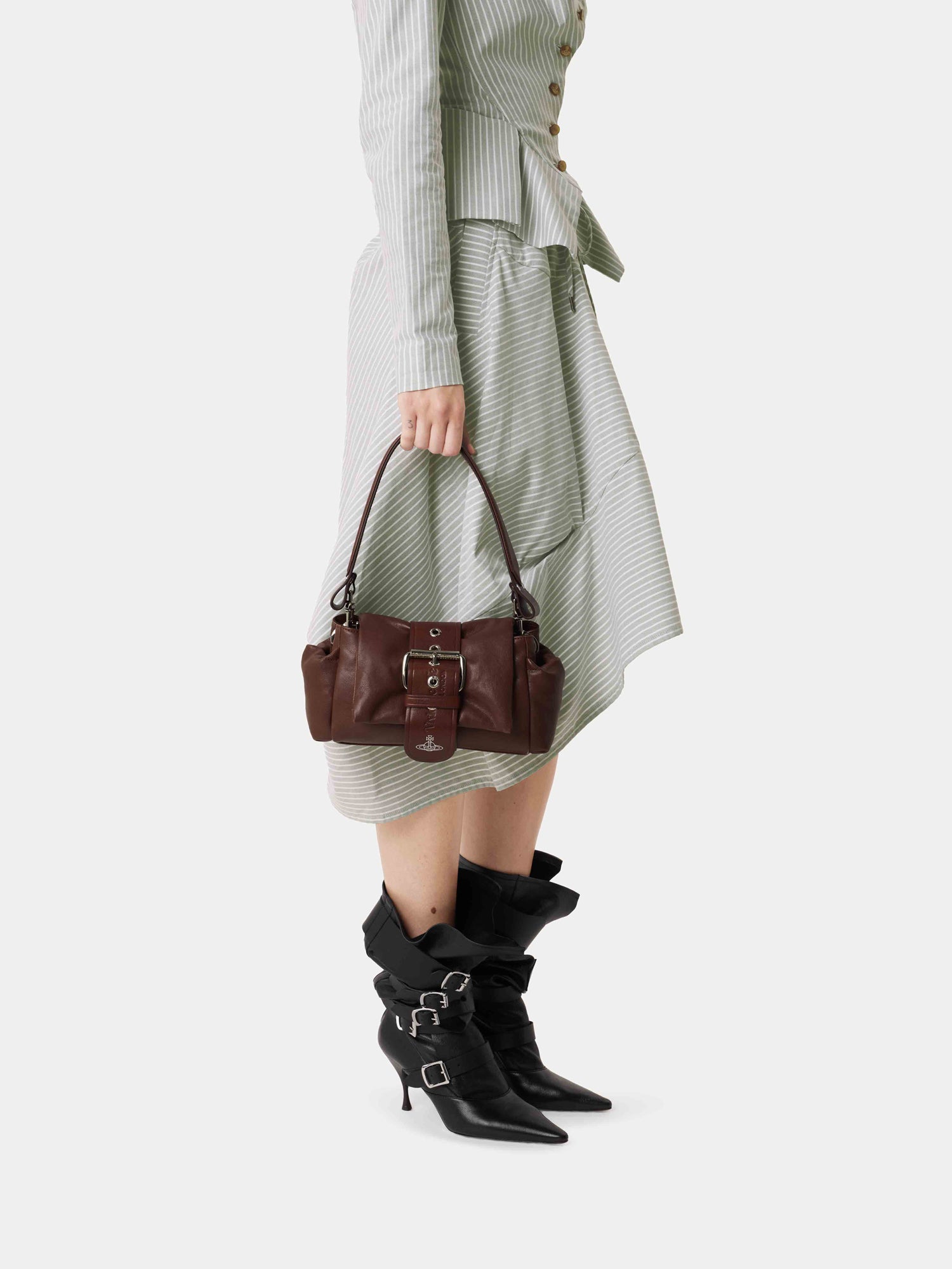 Model carrying Vivienne Westwood Hazel Treasure Handbag in chestnut brown leather with ruched silhouette, chain strap and punk pocket details