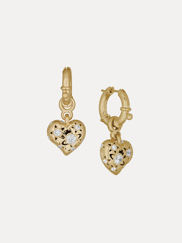 Gold heart-shaped earrings with diamond accents on a light beige background