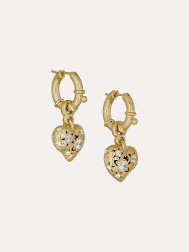 Gold heart-shaped earrings with intricate designs on a light beige background