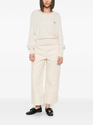 Model wearing Pamela Jumper in Cream by Vivienne Westwood, full-length front view of relaxed-fit cream cotton jumper with draped cowl neck and multicolour Orb embroidery, Spring/Summer 2026