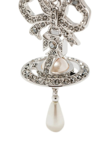 Close up of the silver earrings with bow and orb designs and pearl drops from Vivienne Westwood on a white background