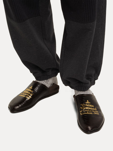 Dark brown shoes with gold text worn from Vivienne Westwood on a white background