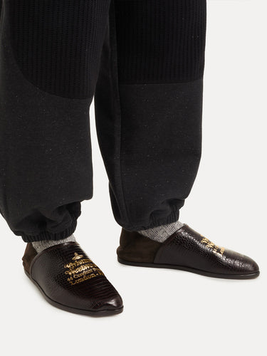 Dark brown shoes with gold text worn from Vivienne Westwood on a white background