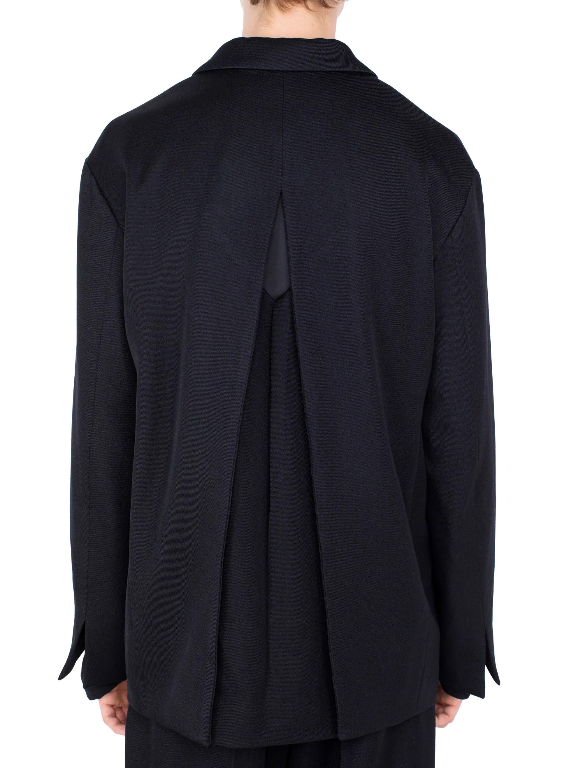 Back view of Kiko Kostadinov Votive Zip Blazer in black wool twill showing pleated back construction, rhombus panel and side vent detailing