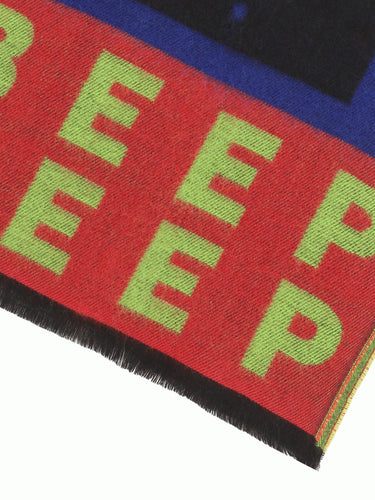 Close-up of a pink scarf from Walter Van Beirendonck with green text on a white background