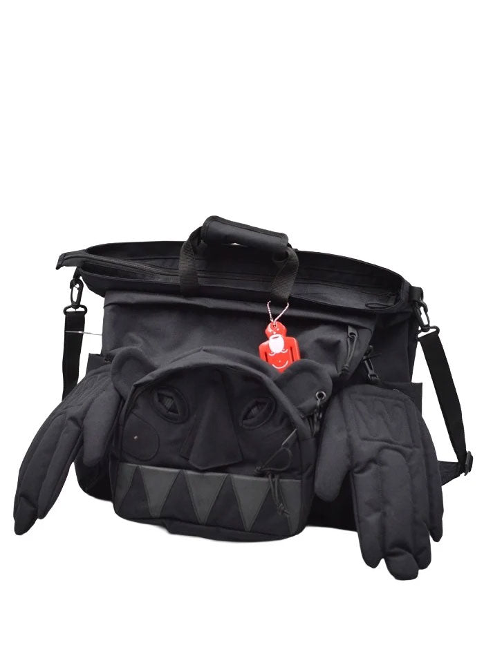Walter Van Beirendonck Monster Carry Bag in black with sculptural monster face, triangular teeth, padded side hands and red character charm.