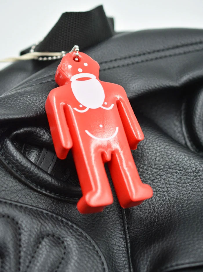 Close-up of the red character charm attached to the Walter Van Beirendonck Walter Pak'r black faux leather backpack.