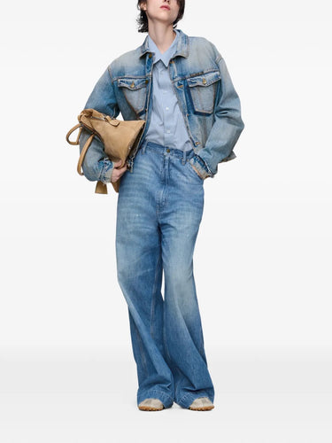 Full-body front view of a female model styled in the Maison Margiela Women’s Sports Jacket in Light Blue Indigo, paired with casual bottoms, showcasing the cropped, frayed denim silhouette.