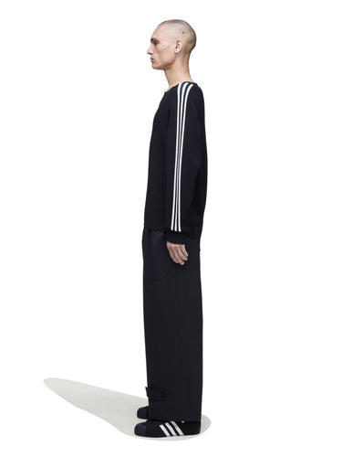 Side view of a male model wearing the Y-3 Logo Knit Sweatshirt in Black, emphasizing the drape of the knit fabric and relaxed silhouette.