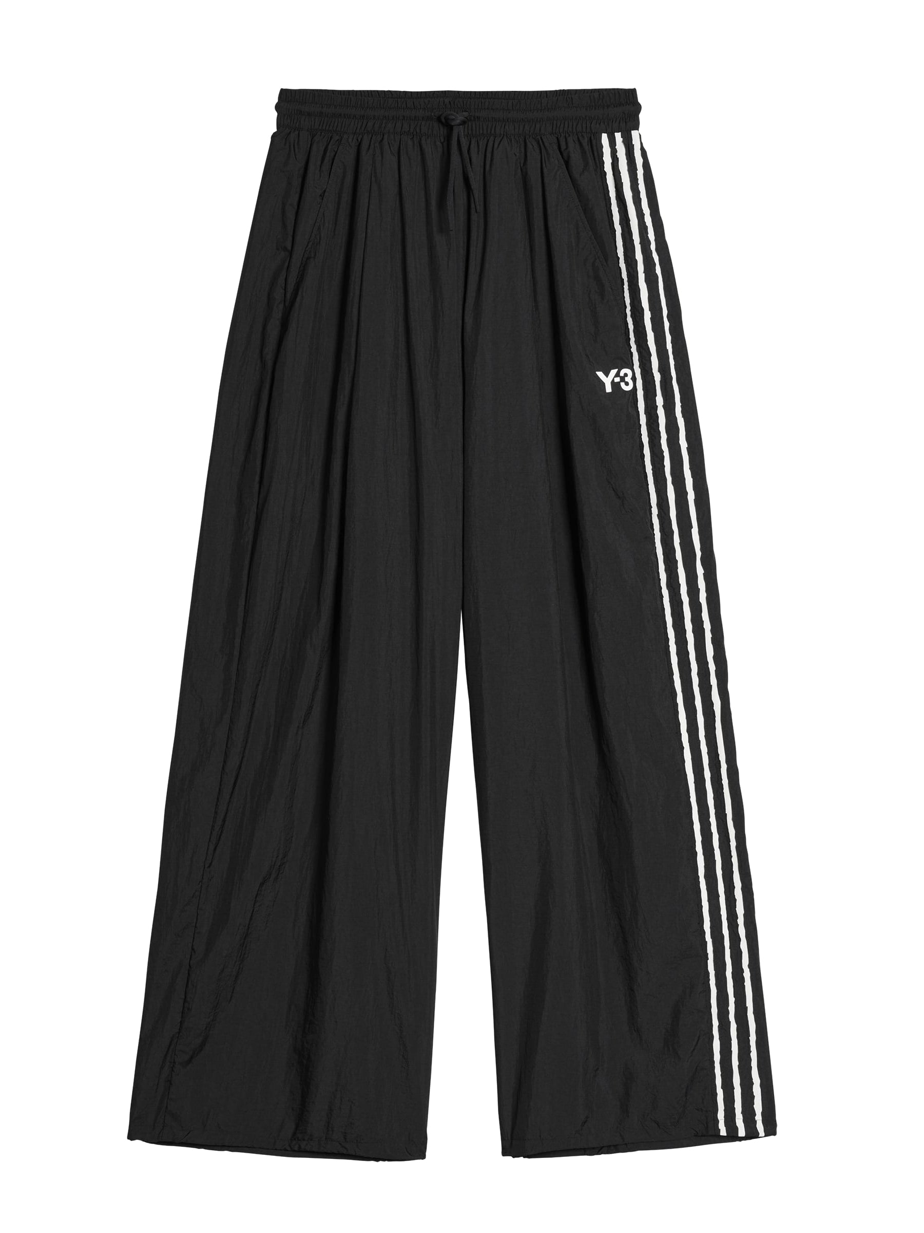Front packshot of the Y-3 Raw Edge 3-Stripes Wide Tracksuit Bottoms in Black, showing the wide, loose silhouette, elasticated waistband with drawcord, angled side pockets, satin heat-transfer Y-3 logo, and adjustable bungee-cord hems.
