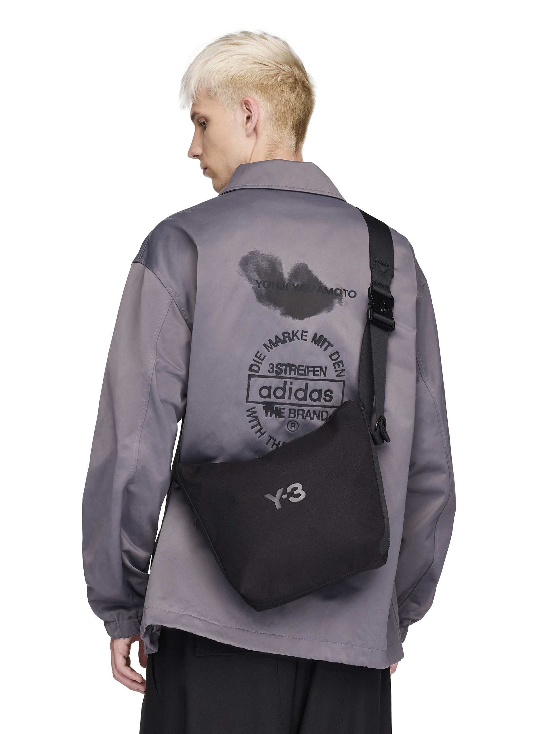 Male model wearing the Y-3 Small Crossbody Bag in Black crossbody style, showing the compact size and adjustable strap.