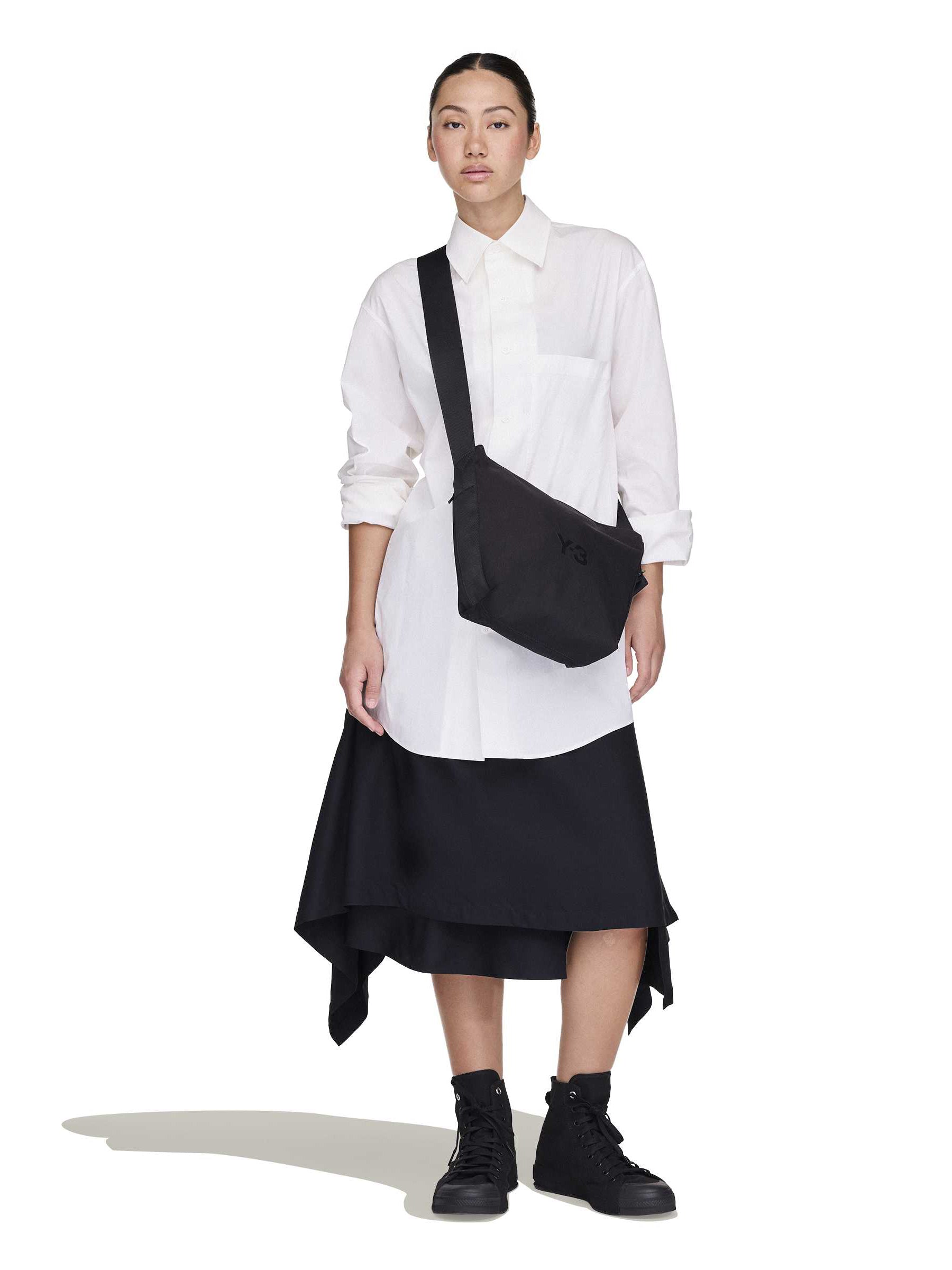 Female model wearing the Y-3 Small Crossbody Bag in Black, styled over the shoulder to highlight its versatile design.