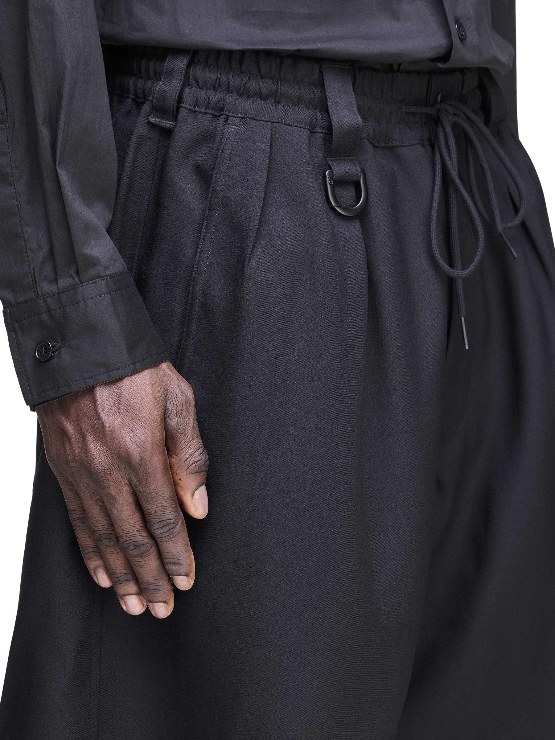 Close-up side view of a male model wearing the Y-3 Sport Uniform Cargo Shorts in Black, emphasizing the fabric texture and utilitarian styling.