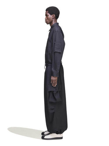 Side view of a male model wearing the Y-3 Sport Uniform Wide Cargo Trousers in Black, emphasizing the relaxed wide-leg cut, cargo pockets, and D-ring detail at the waistband.