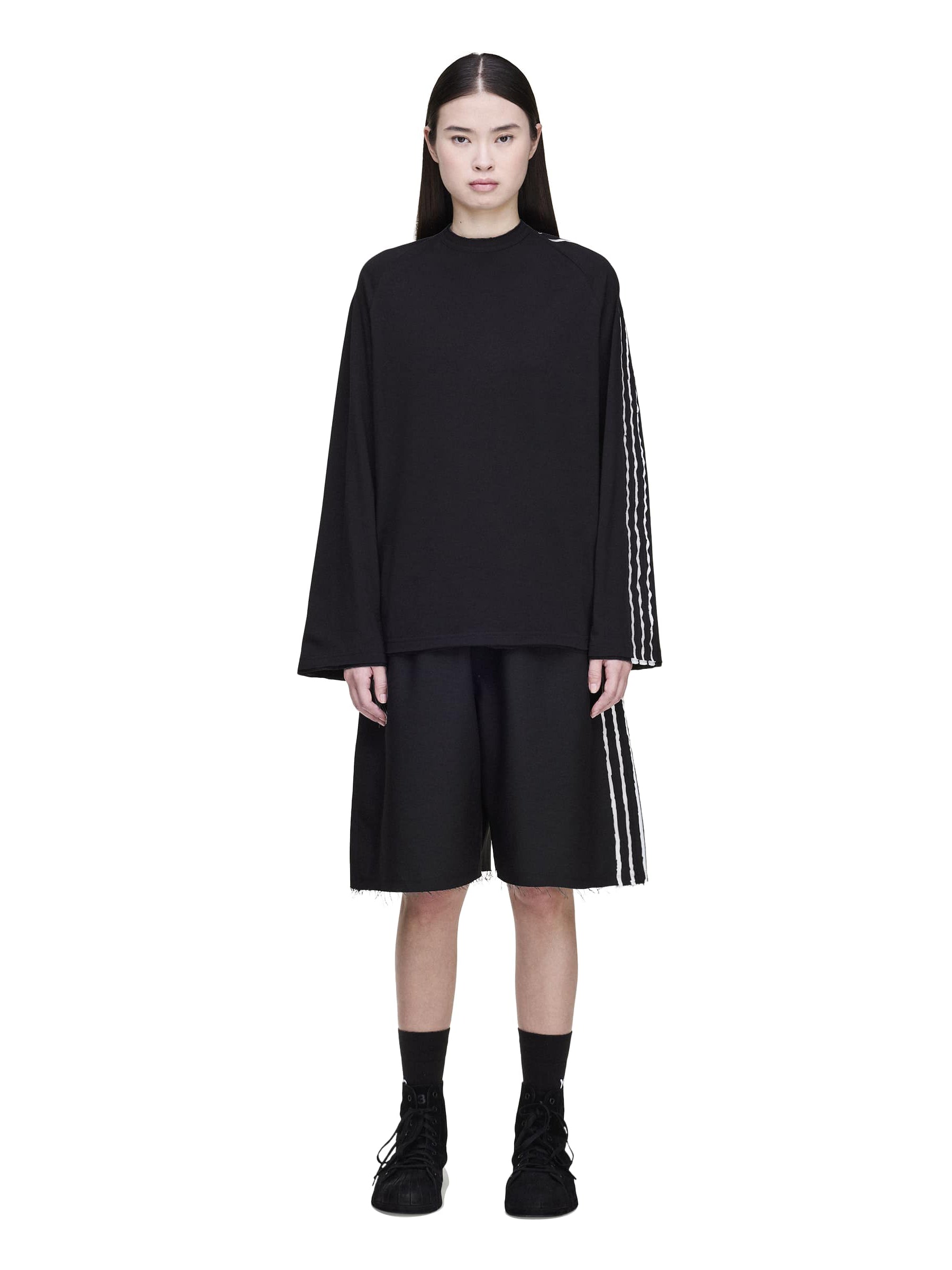 Female model wearing the Y-3 Summer Run 3-Stripes Shorts in black from the front, highlighting the raw-cut 3-Stripes and contemporary silhouette.
