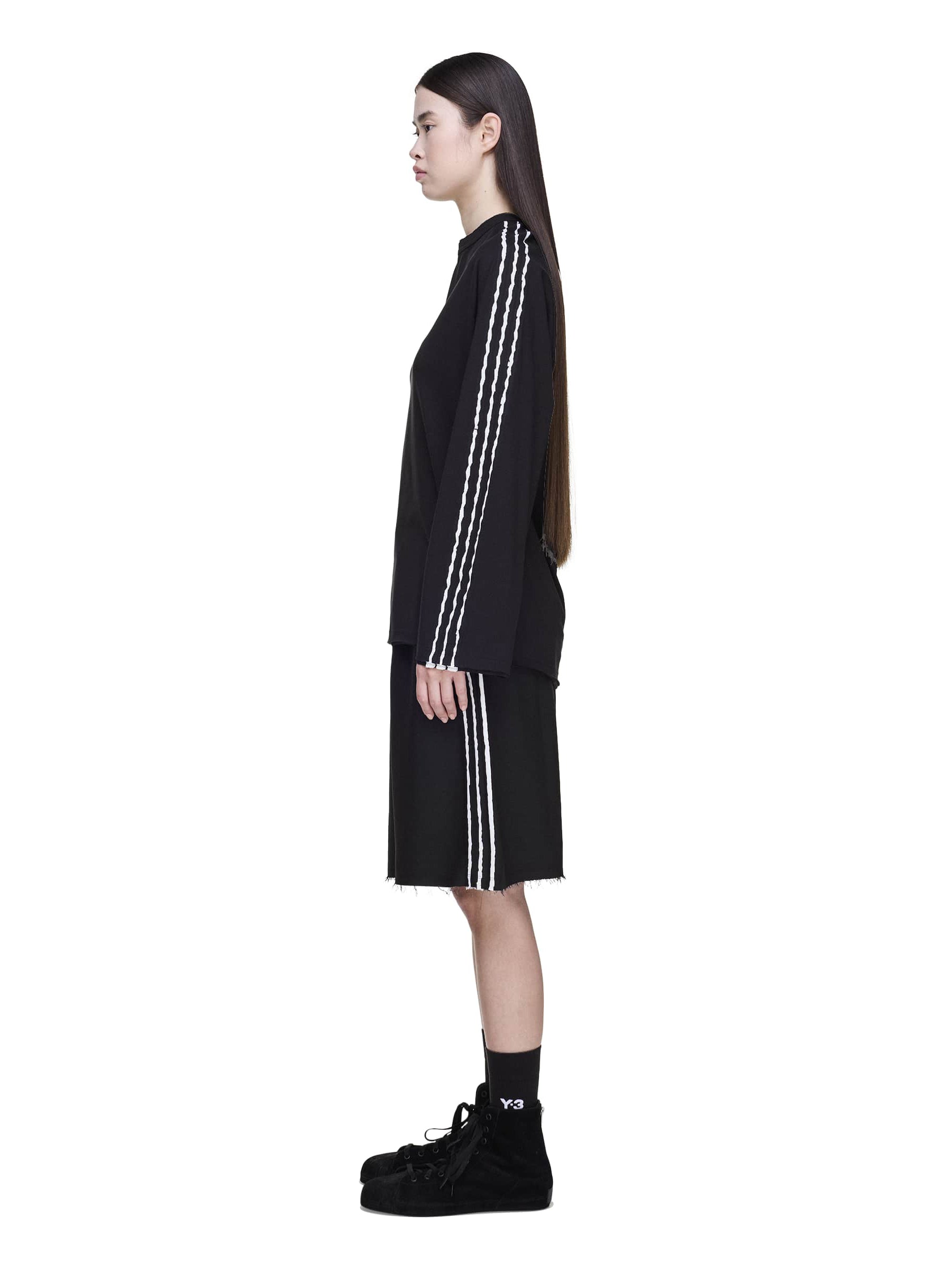 Side view of a female model wearing the Y-3 Summer Run 3-Stripes Shorts in black, showing the elastic waistband and side welt pocket.
