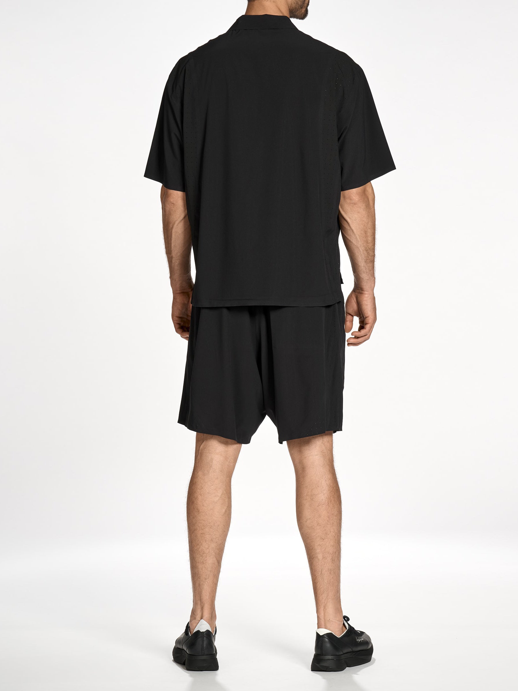 Back view of a male model wearing the Y-3 Ultralight Woven Shirt in Black, highlighting the clean rear silhouette and subtle tonal Y-3 logo.”