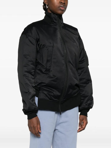 Person wearing a black bomber jacket on a white background