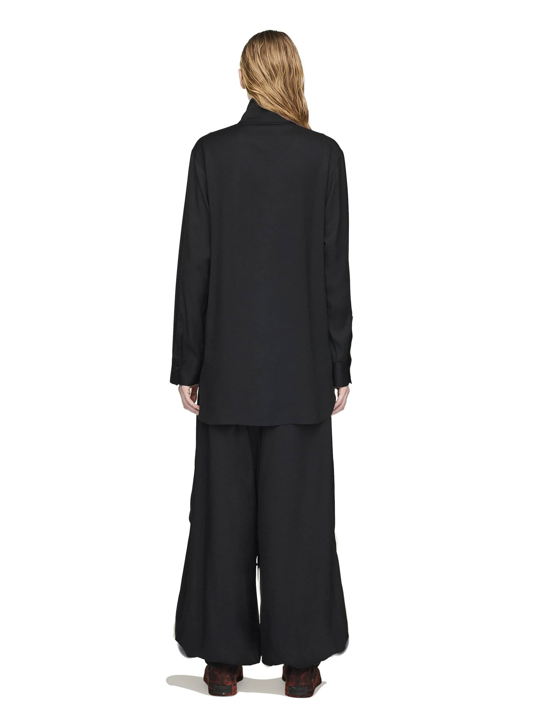 Person wearing a black outfit with wide-leg pants on a white background